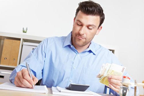 © Robert Kneschke - stock.adobe.com Foto: Mann mit Stift und Geldscheinen in den Händen