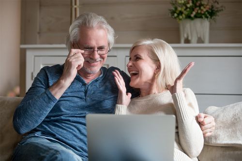 © fizkes - stock.adobe.com Foto: Zwei Pensionisten sitzen auf einer Couch mit einem Laptop