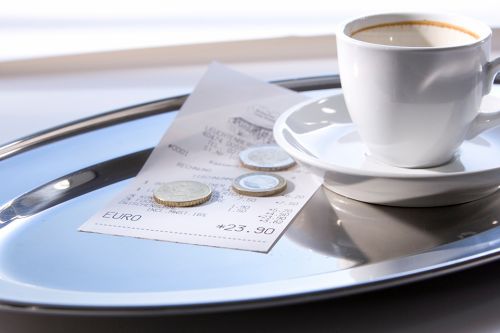 © 0pidanus - stock.adobe.com Foto: Trinkgeld auf Tablett mit leerer Kaffeetasse